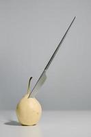 Knife that is stuck in a pear photo