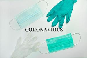 Medical protective masks with gloves on the table with Coronavirus word photo