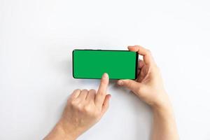 Woman holding a green screen mobile phone with a white background photo