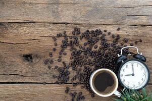 Wooden desk with coffee beans and alarm clock photo