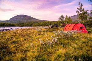 Red camping tent by a river photo