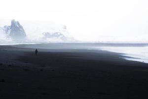 blanco y negro de una persona caminando en la playa foto