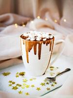 White mug with caramel sauce and marshmallows photo