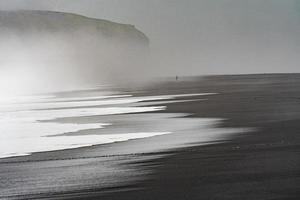 Black beach shore with fog photo