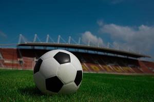 Soccer ball on grass with stadium background photo