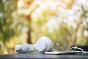 White headphones on wooden table with nature background