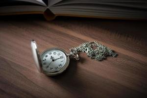 Close-up of a golden pocket watch and a book