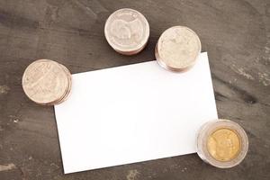 Tarjeta de nombre en blanco con monedas sobre una mesa foto