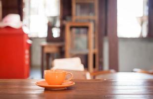 Taza de café naranja sobre una mesa en un café foto