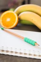 Notebook and pencil with fruit photo