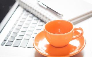 Orange coffee cup on a computer photo