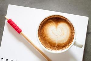 Top view of a latte with a pencil on a notebook photo