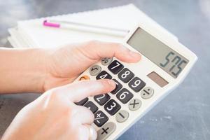 Hands holding and pushing buttons on a calculator photo