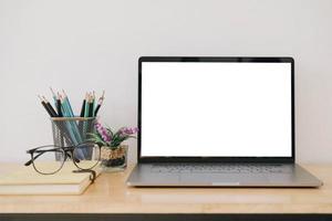 Pantalla de ordenador portátil en blanco en el escritorio con suministros de espacio de trabajo foto