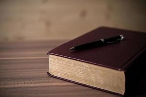 Book with a pen on wooden table photo