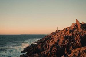 White lighthouse over huge risky rocks photo