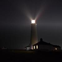 Lighthouse under starry night photo
