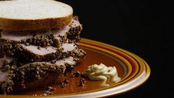 Foto giratoria de un delicioso sándwich de pastrami premium junto a una cucharada de mostaza de Dijon - comida 047 video