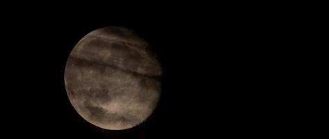 Nocturnal scene of full moon moving from left to right with heavy clouds in foreground in 4K video