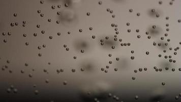 modello di piccole bolle in primo piano e bolle sfocate in movimento veloce su sfondo grigio in 4K video