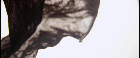 dunkler Stoff, der sich langsam auf klarer Flüssigkeit und hellem Hintergrund in 4k bewegt video