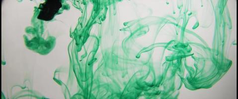 Green ink moving slowly in clear liquid smoke creating wonderful thin lines in 4K video