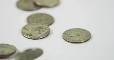  A lot of coins of quarter dollar falling and spinning over three coins on white table, six coins placed in the scene in 4K video