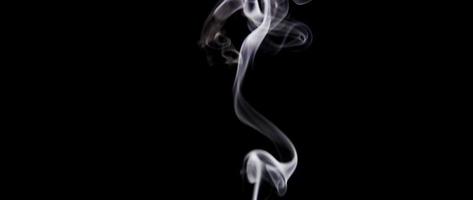 Thin lines of white smoke drawing swirls and waves on dark background in 4K video