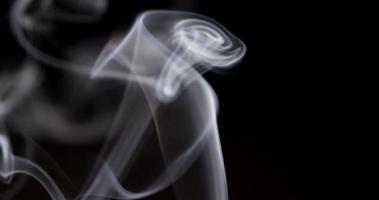 Close up of thin smoke lines dancing with hypnotic movements on dark background in 4K video