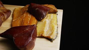 Foto giratoria de una variedad de deliciosas carnes ahumadas de primera calidad en una tabla de cortar de madera - comida 076