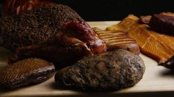 Rotating shot of a variety of delicious, premium smoked meats on a wooden cutting board - FOOD 063 video