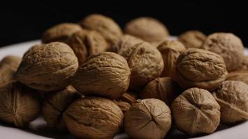Cinematic, rotating shot of walnuts in their shells on a white surface - WALNUTS 084