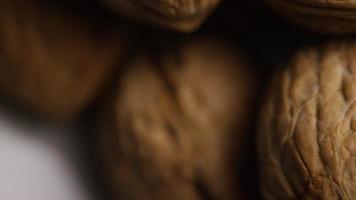 Cinematic, rotating shot of walnuts in their shells on a white surface - WALNUTS 061 video