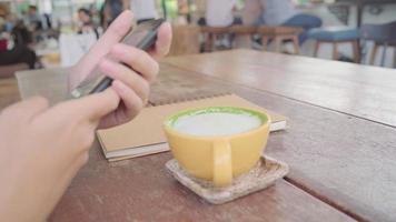 Female blogger photographing green tea cup in cafe with her phone. video