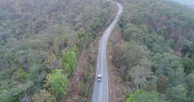 Vue aérienne d'une voiture qui traverse une route forestière video