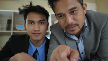 Two businessmen looking and analyzing business chart on monitor video