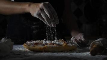 slow motion van de handen van een vrouw die bloem over een pizza zift video