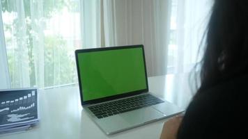 Close-up of a woman's hands coming on a laptop with green screen placeholder