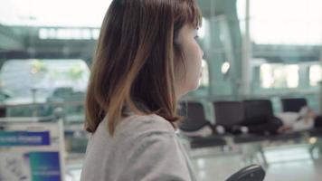 attraktiv avslappnad glad ung asiatisk kvinnlig passagerare i internationell flygplats.