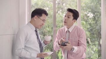 Young smiling men drinking coffee in the office. video