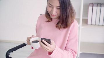 Aziatische vrouw in slimme vrijetijdskleding met behulp van smartphone en koffie drinken. video