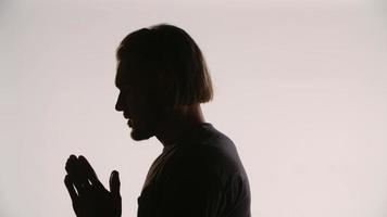 Silhouette of a young white man praying  and tilting his head up video