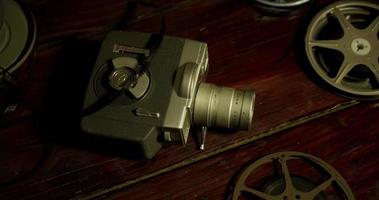 Short panning shot of four film reels, a can and an ancient camera on a table in 4K video