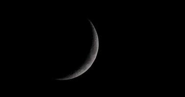 Dark waxing crescent moon moving in night sky from top to bottom of the scene in 4K