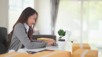 Joven mujer asiática trabajando en un portátil y sonriendo video