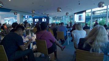 Slow panning shot of a room with people sitting taking a comshop video