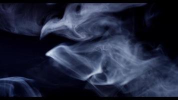 Soft smoke moving slowly drawing thin lines and waves on dark background in 4K video