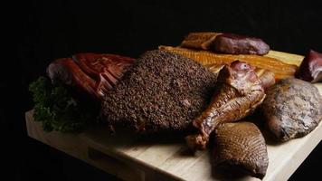 Rotating shot of a variety of delicious, premium smoked meats on a wooden cutting board - FOOD 061 video