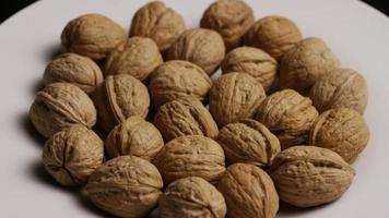 Cinematic, rotating shot of walnuts in their shells on a white surface - WALNUTS 011 video