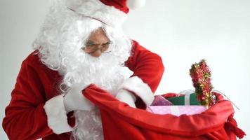 santa claus vistiendo un traje rojo y preparando una bolsa de regalo video